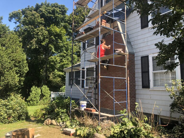 Mason restoring brick chimney on exterior of a house